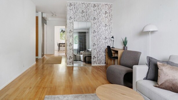 Una sala de estar moderna con piso de madera, un sofá gris, una mesa de centro y un escritorio con una silla.