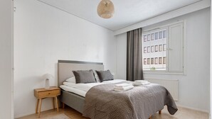 Un dormitorio con cama, mesita de noche y ventana con persianas.