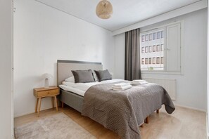 Ein Schlafzimmer mit Bett, Nachttisch und einem Fenster mit Jalousien.