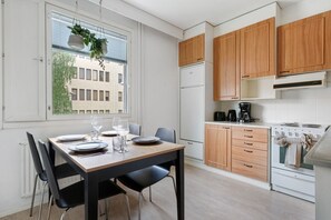 Eine moderne Küche mit Holzausbau, einem Esstisch für vier Personen und einem Fenster mit Blick auf Gebäude.