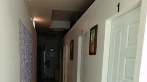 A hallway with a patterned floor, white doors, and a number sign. - Del Mar Hotel (Pattaya)
