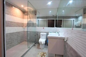 A modern bathroom with a glass shower enclosure, a toilet, and a sink. - Del Mar Hotel (Pattaya)