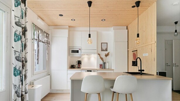 Una cocina moderna con una isla central, armarios blancos e iluminación colgante.