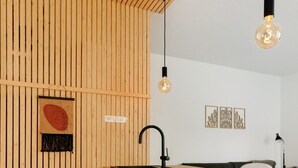 Una cocina con paredes de listones de madera, encimera de madera, grifo negro y lavavajillas Siemens.