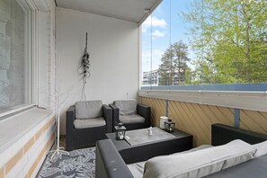 Ein Balkon mit zwei Sofas, einem kleinen Tisch und einer hängenden Pflanze.