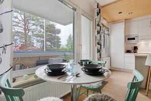 Eine moderne Küche mit Esstisch, Stühlen und Blick auf Bäume.
