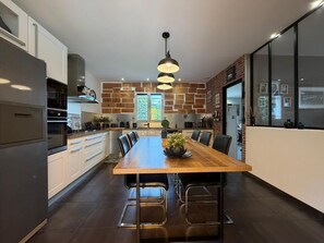 A modern kitchen with a large island, pendant lighting, and a brick accent wall. - La Villa Ametza - Swimming pool (MOUGUERRE)