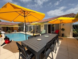 A poolside area with a table and chairs, yellow umbrellas, and a swimming pool. - La Villa Ametza - Swimming pool (MOUGUERRE)