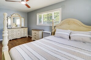 Een slaapkamer met een bed, een kaptafel, een spiegel en een raam.