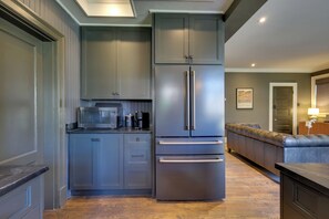 Una cocina con microondas integrado, cafetera y refrigerador de acero inoxidable.