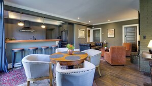 Een moderne keuken met barstoelen, een eettafel met stoelen en een zithoek met een bank en fauteuils.