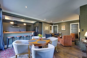 Una cocina moderna con taburetes de bar, una mesa de comedor con sillas y una sala de estar con sofá y sillones.