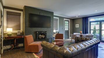 A living room with a fireplace, leather sofa, and a flat-screen TV.