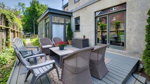Een terras buiten met rieten meubels, een tafel en potplanten.