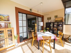 Ein Essbereich mit Tisch, Stühlen, einem Schrank und einem Bücherregal.