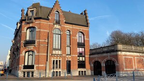Een historisch gebouw met meerdere ramen, een balkon en een hekwerk.