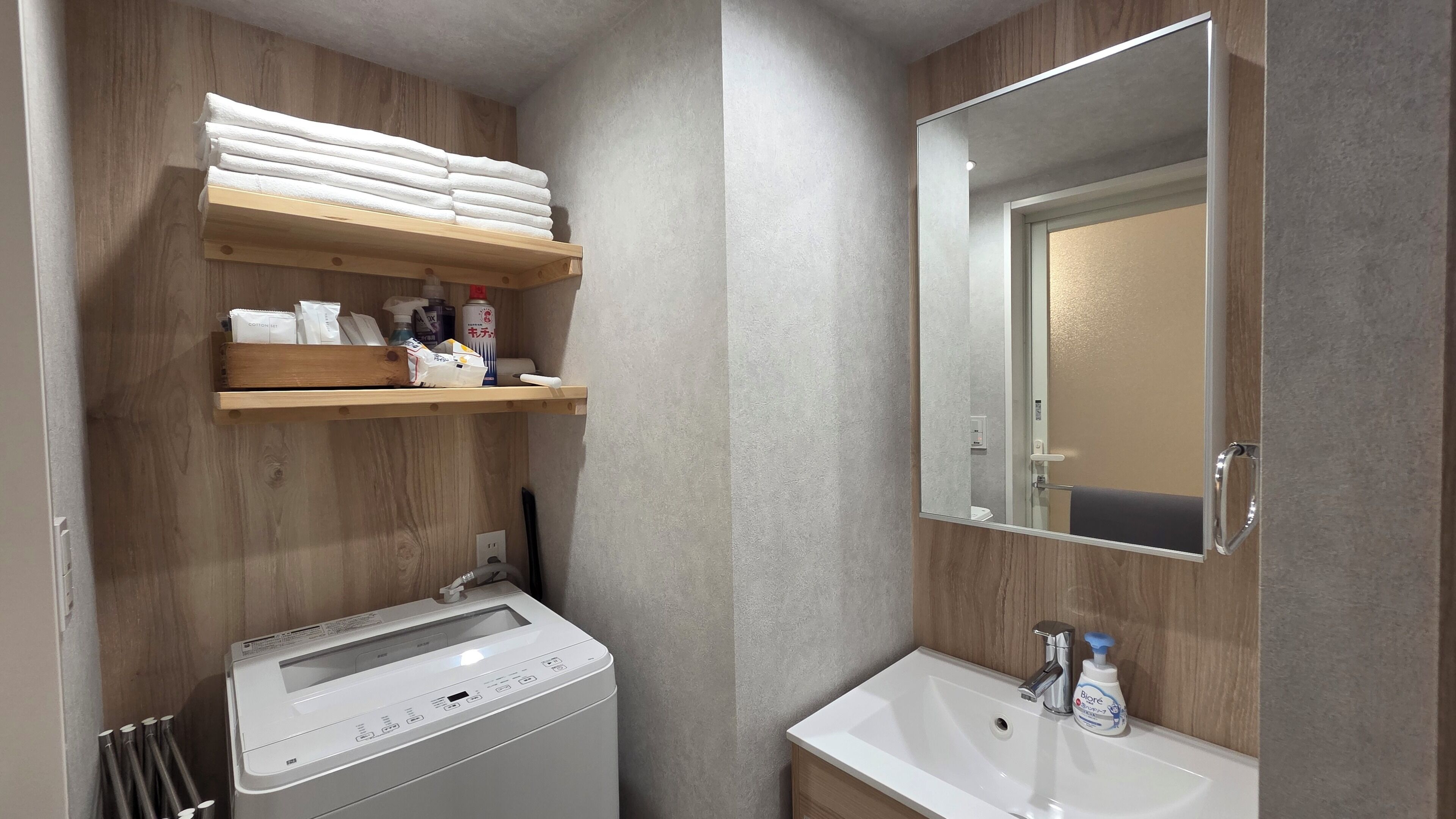 Une salle de bain équipée d’un lave-linge, d’un lavabo et d’un miroir.