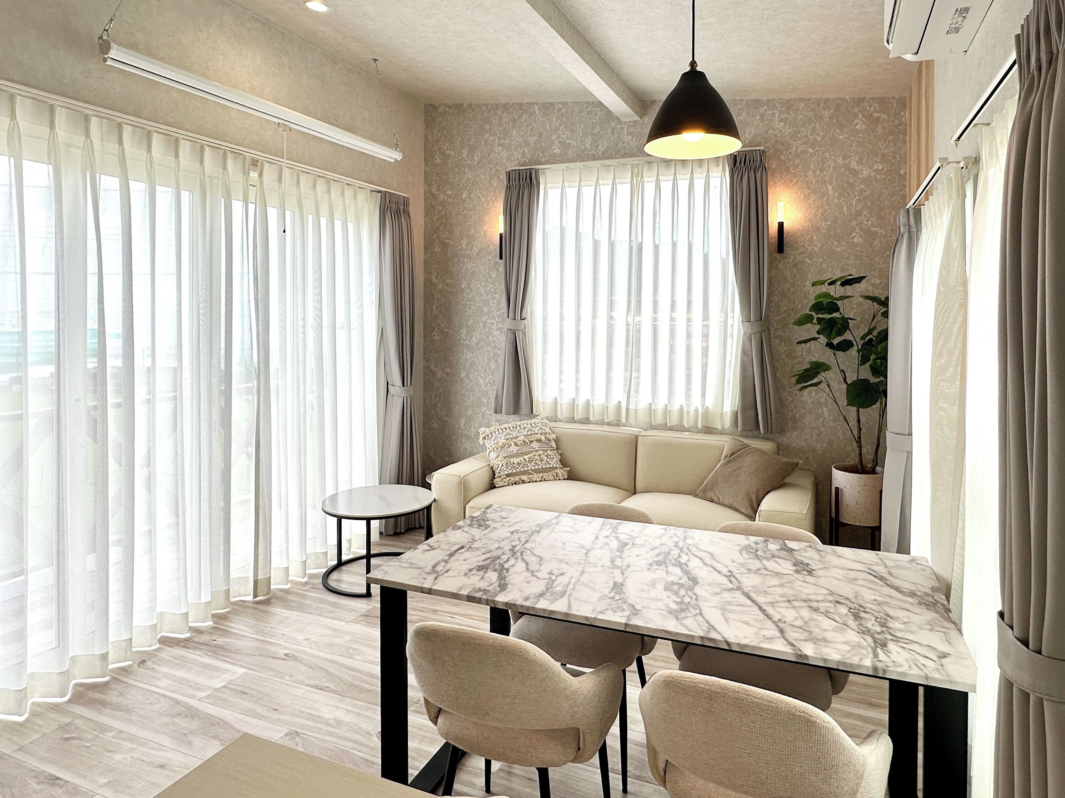 Una sala de estar moderna con un sofá, una mesa de comedor de mármol y sillas.