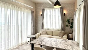 A modern living room with a sofa, a marble dining table, and chairs. - Solana Beach Villa Minamiboso (Minamiboso)
