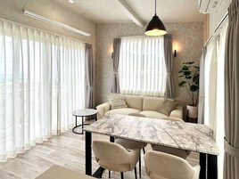 Una sala de estar moderna con un sofá, una mesa de comedor de mármol y sillas.