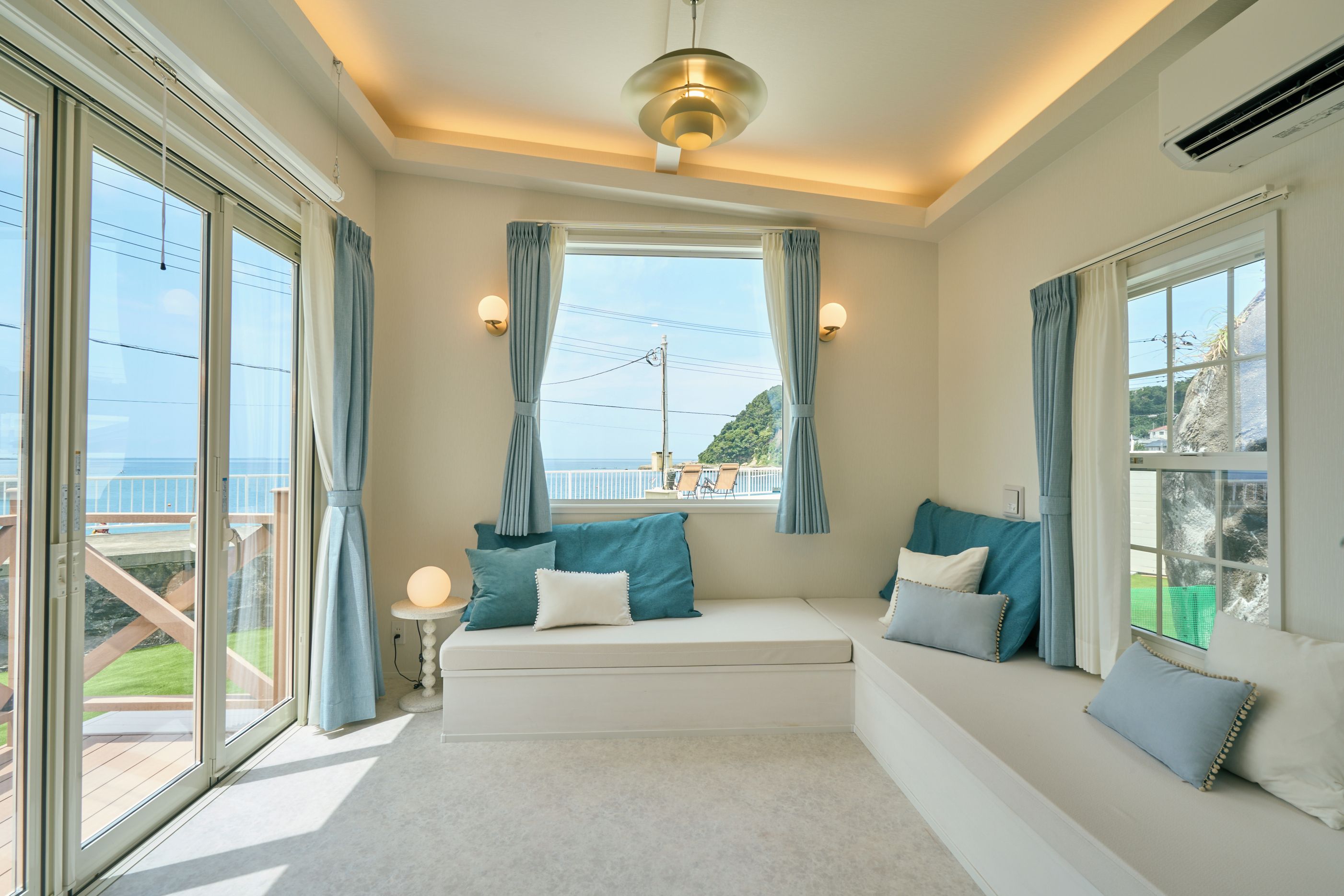 Una habitación con un ventanal grande, una lámpara de techo y vistas al mar.
