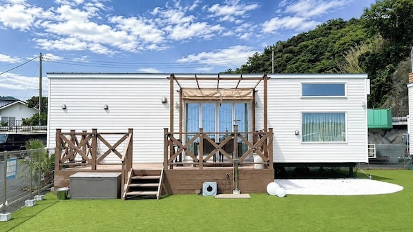 A mobile home with a deck, a window, and a small outdoor area.