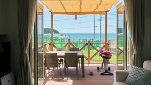Una habitación con vista al mar, un patio con mesa y sillas, y una parrilla.