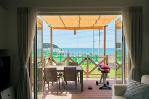 Una habitación con vista al mar, un patio con mesa y sillas, y una parrilla.