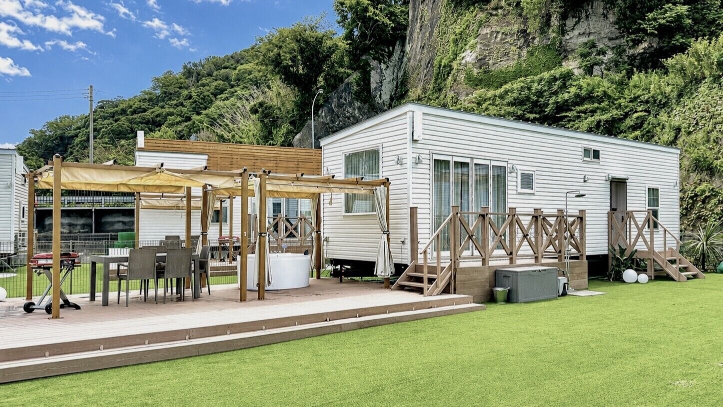A mobile home with a patio area, outdoor seating, and a wooden deck.
