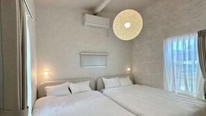 A hotel room with two beds, a ceiling fan, an air conditioning unit, and a window with curtains. - Solana Beach Villa Minamiboso (Minamiboso)