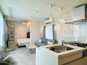 Una habitación de hotel moderna con kitchenette, una cama, un sofá y un comedor.