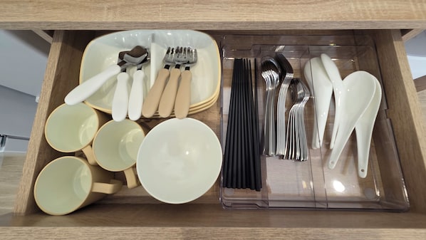 A drawer containing various utensils and bowls.