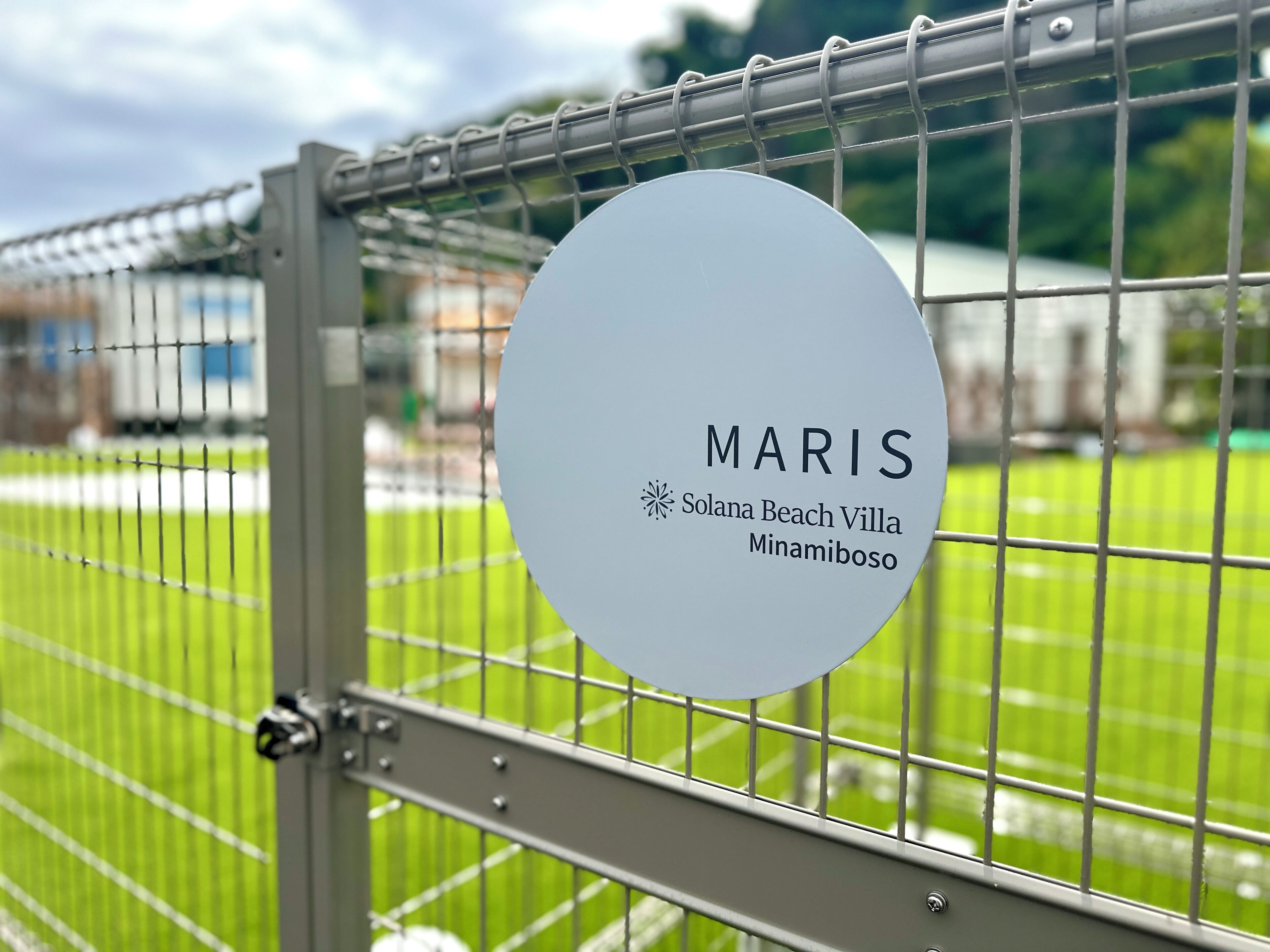 Une porte en métal sur laquelle est fixée une plaque circulaire portant l’inscription : « MARIS Solana Beach Villa Minamboso ».