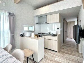 Une cuisine moderne dotée d’une cuisinière intégrée, d’une fenêtre au-dessus de l’évier et d’un coin repas avec une table et des chaises.