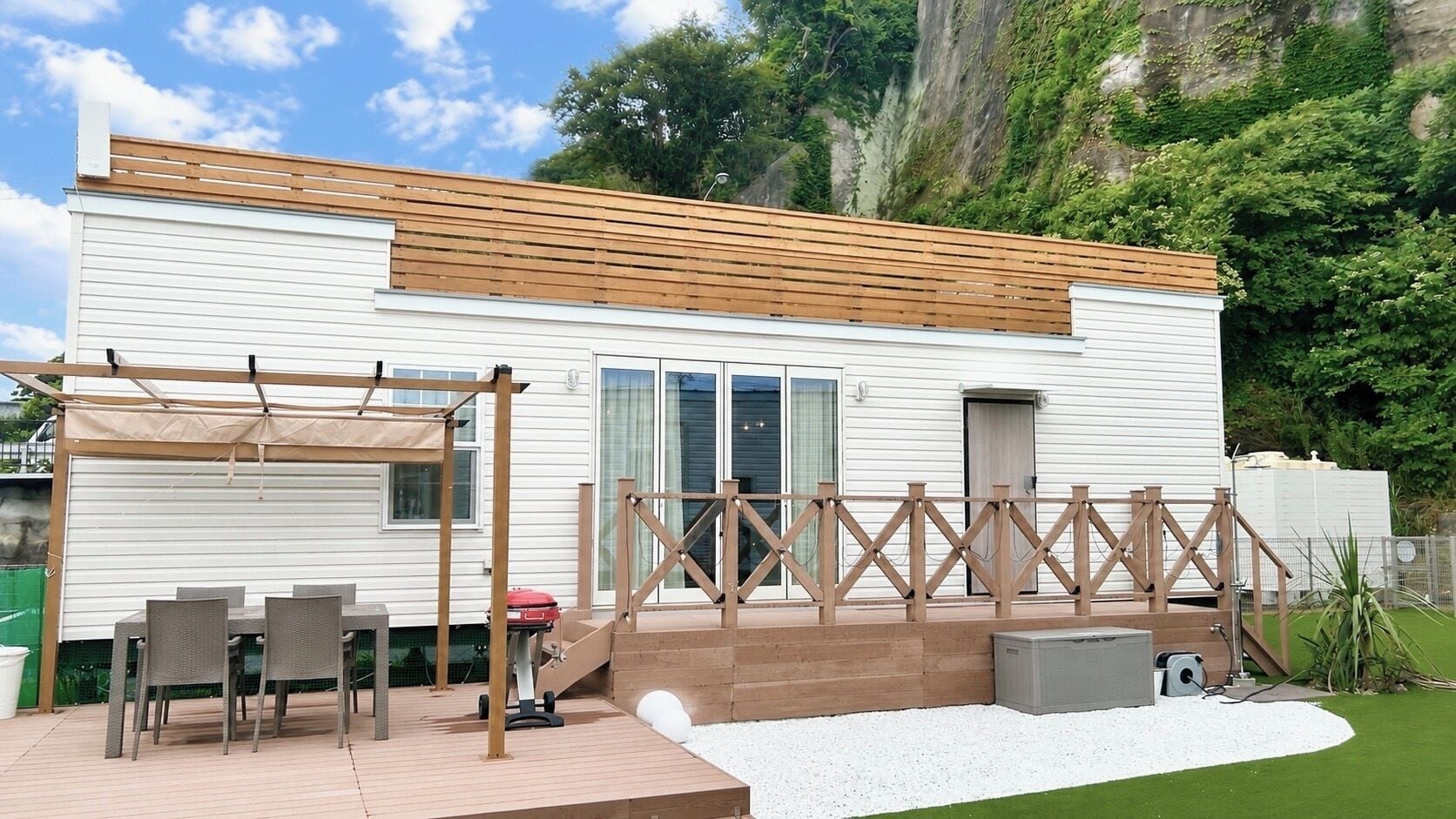 A modern house with a patio area, outdoor furniture, and a wooden deck.