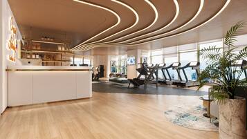 Ein modernes Fitnessstudio mit Trainingsgeräten, einer Rezeption und großen Fenstern.