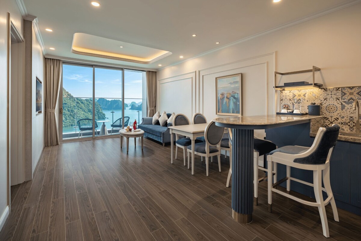 A modern kitchen with a dining area, large windows, and a view of the outdoors.