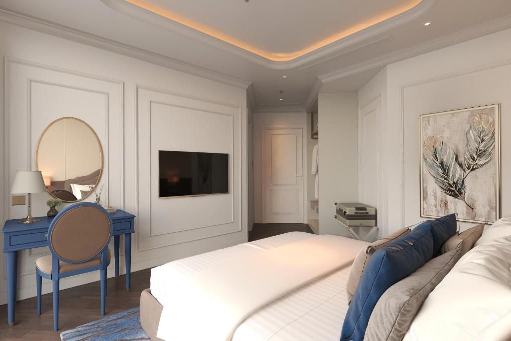 A hotel room with a bed, a desk with a chair, a television, and a painting on the wall.
