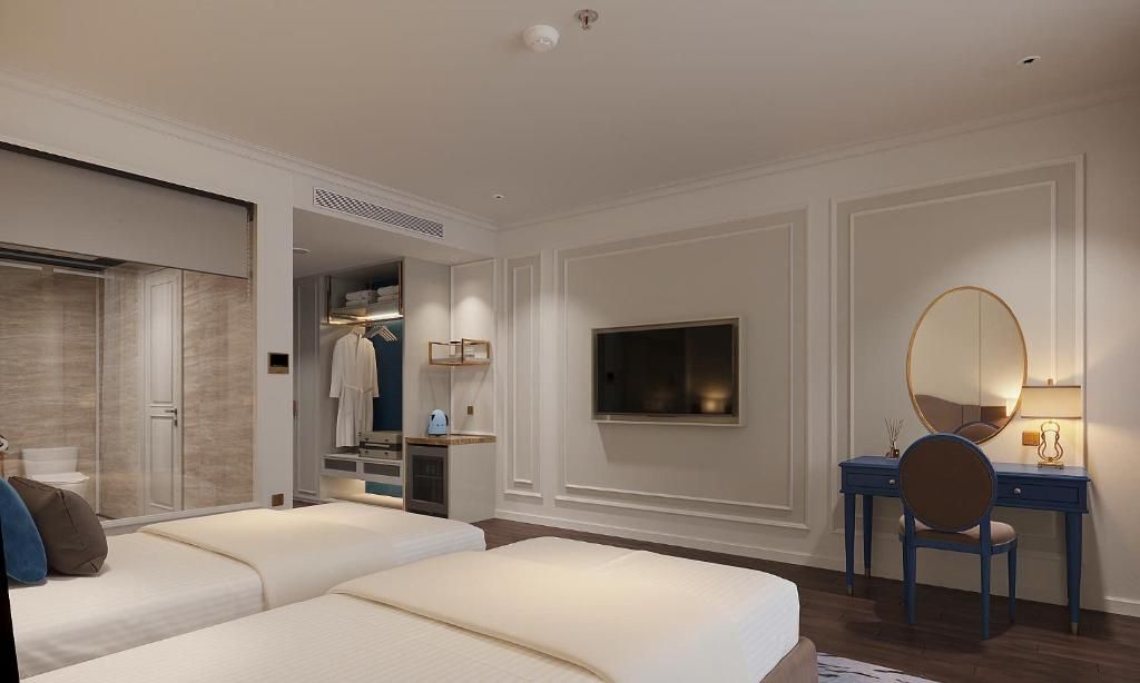 A hotel room with two beds, a desk with a chair, a mirror, a television, and a wardrobe.