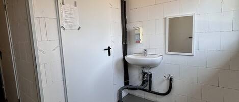 A restroom with white brick walls, a white sink, and a door with a notice taped to it.