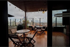 An outdoor seating area with tables and chairs, a wooden ceiling, and a view of the cityscape. - Apartment with Pool and 360 Degree View (Bogotá)