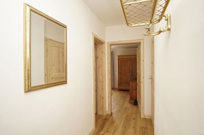 Ein Korridor mit einem großen Spiegel, Holztüren und einem Holzschrank.