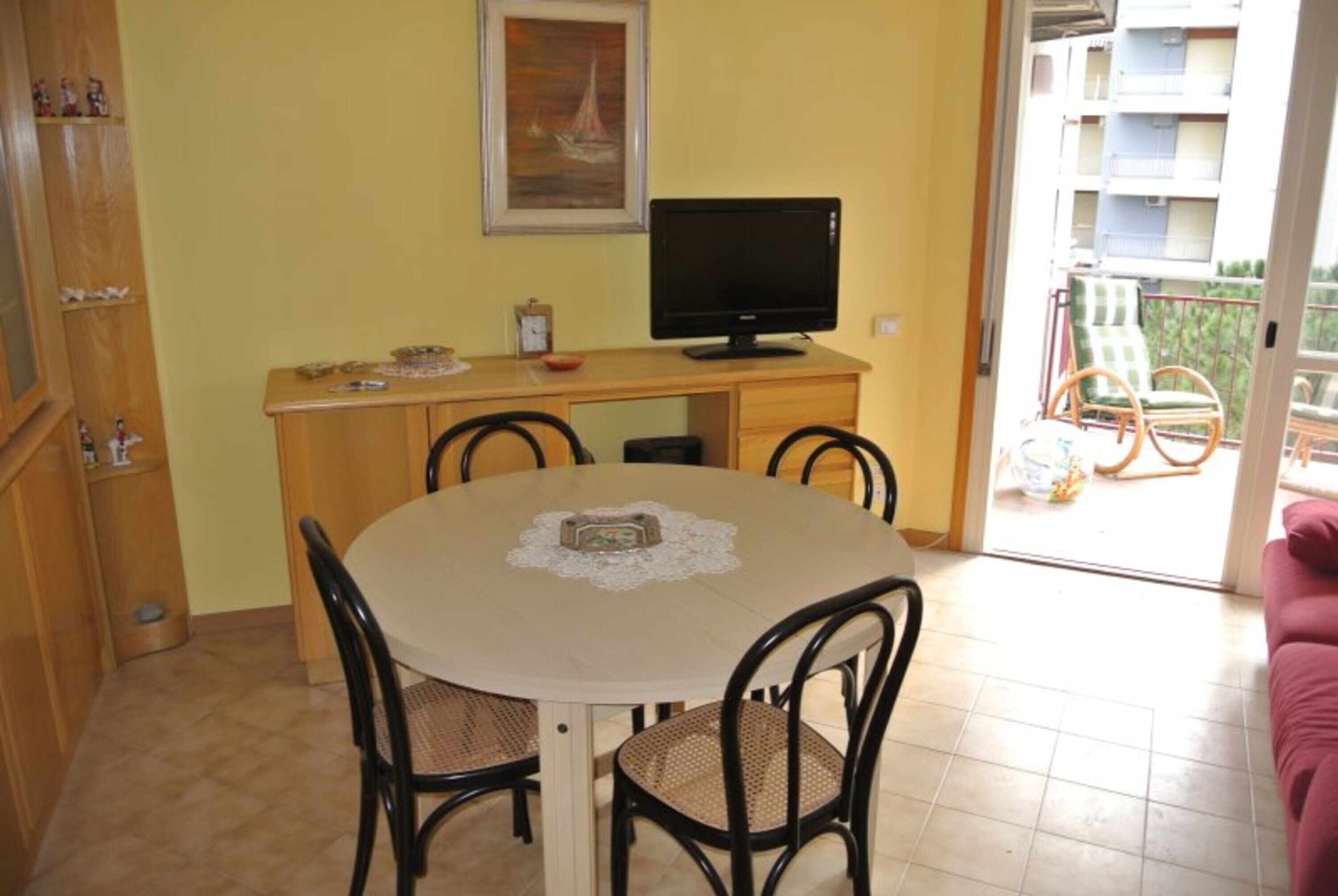 Ein Essbereich mit einem runden Tisch, Stühlen, einem Fernseher und einem Bild an der Wand.
