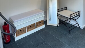 Une pièce comprenant une commode blanche, un miroir, un tableau encadré, une petite table et un extincteur.