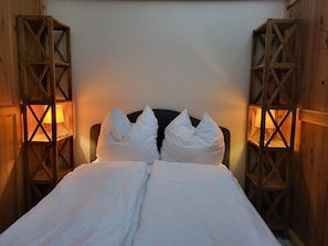 A bed with white bedding and pillows, flanked by wooden structures with lamps. - Alter Reichshof, App. 302 - with balcony and sea view - Alter Reichshof, App. 302 (Sassnitz auf Rügen)