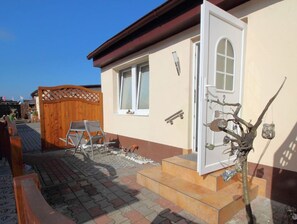 Ein Haus mit Holzzaun, einer Tür und einer kleinen Außenbereich-Sitzgelegenheit mit Bank und Tisch.