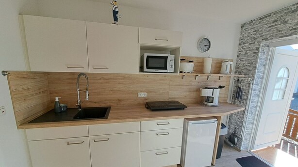 Een kleine keuken met een magnetron, koffiezetapparaat en een kleine koelkast.