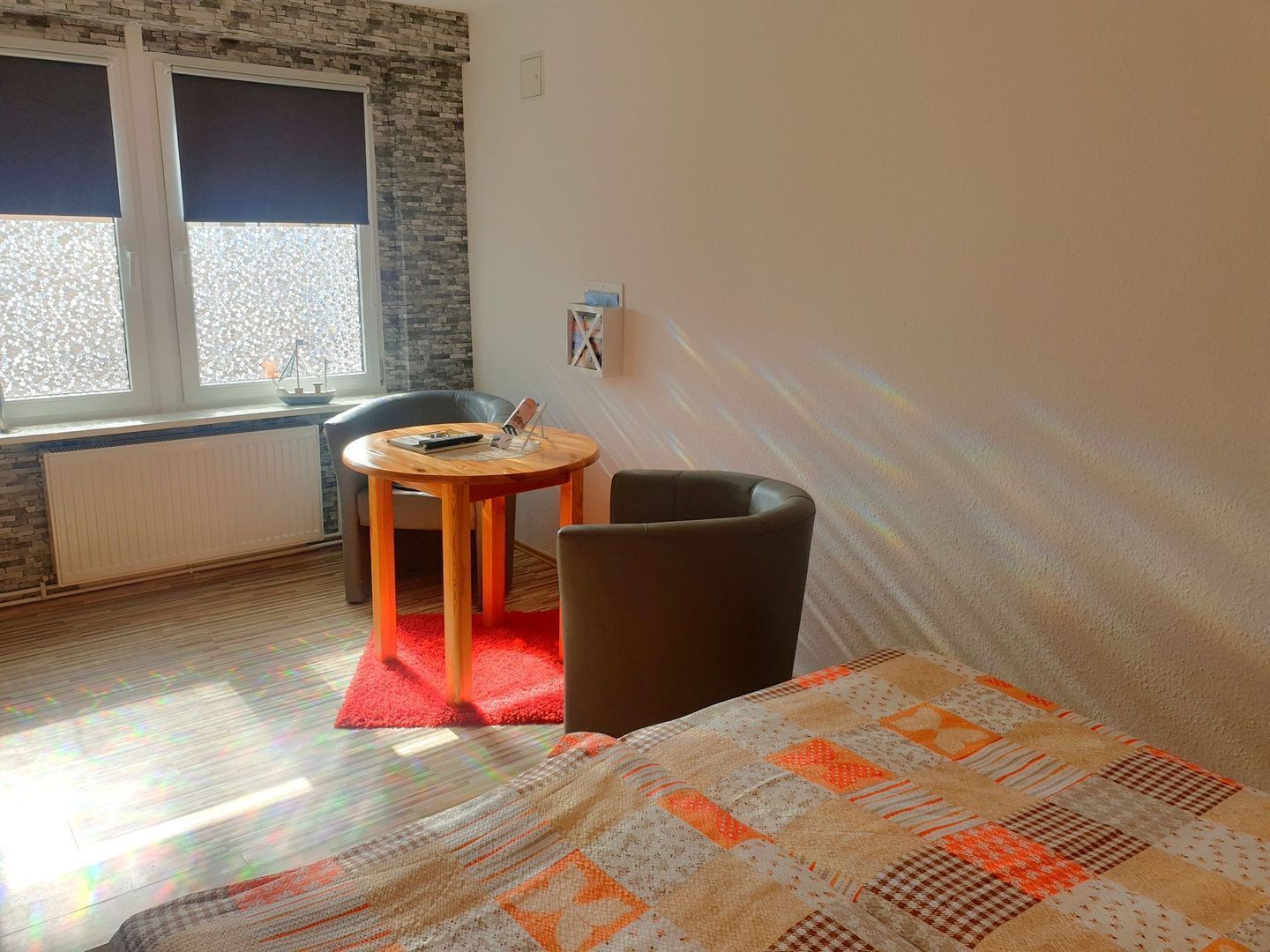 Une pièce comprenant un lit, une petite table ronde avec une chaise, un radiateur et une fenêtre avec des stores.
