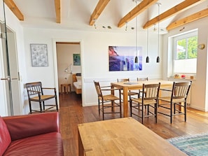 Ein geräumiges Zimmer mit einem Holzespeisetisch, Stühlen, einem roten Sofa und einem großen Gemälde an der Wand.