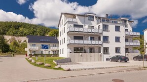 Ein mehrgeschossiges Wohngebäude mit Balkonen, einem Parkplatz und einem Schild, das eine familienfreundliche Umgebung kennzeichnet.
